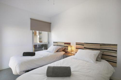 two beds in a room with white walls at Beautiful Duplex Facing The Beach in El Médano