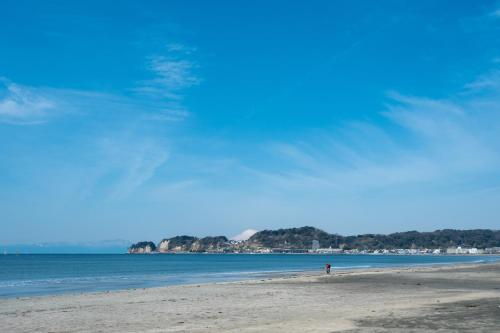 a beach with a person standing on the sand at Kohaku AMBER Kamakura Zaimokuza in Kamakura