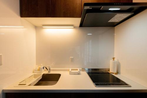 a kitchen with a sink and a microwave at Kohaku AMBER Kamakura Zaimokuza in Kamakura