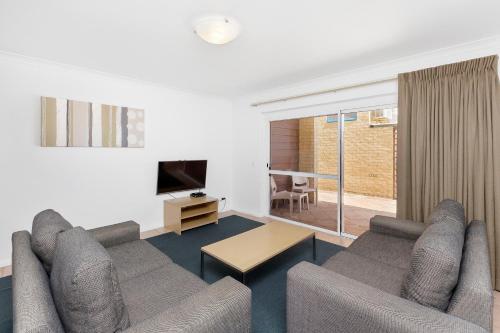 a living room with a couch and a tv at Nautica Residences Hillarys in Perth