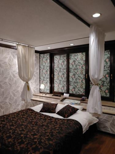 um quarto com uma cama e duas janelas com cortinas em ホテルサバナリゾートＡｄｕｌｔ Ｏｎｌｙ em Kishiwada