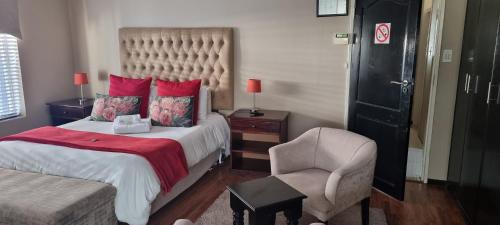 a hotel room with a bed and a chair at Heimat Guesthouse in Welkom