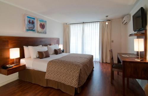 Schlafzimmer mit einem Bett, einem Schreibtisch und einem TV in der Unterkunft Park Plaza Apart Hotel in Santiago