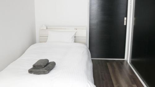 讀谷的住宿－MONOCHROME -SEVEN Hotels and Resorts-，一张白色的床,上面有一条毛巾