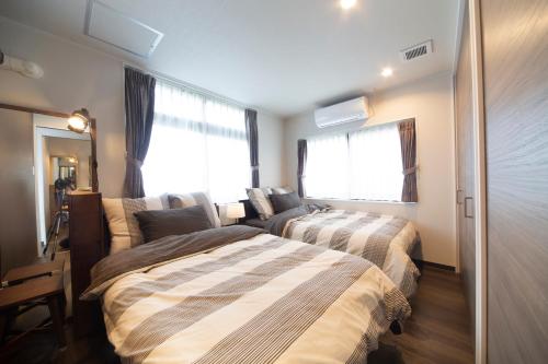1 Schlafzimmer mit 2 Betten und einem Fenster in der Unterkunft 恩納村カーチーベー in Meta