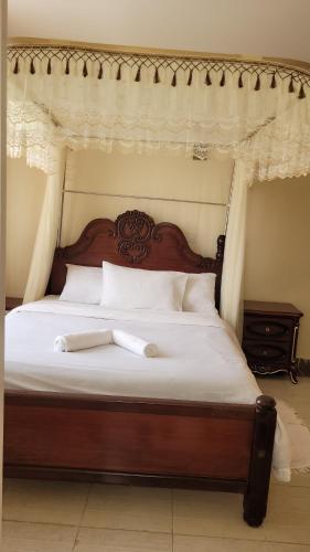 1 cama con cabecero de madera y sábanas blancas en Ree homestay and safaris -JKIA en Nairobi