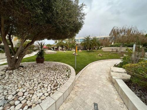 a walkway with a tree in a park at RAG Marine Winner - Lovely Sea Front luxury in Herzliya B