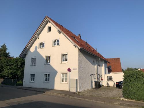 une maison blanche avec un toit rouge dans une rue dans l'établissement FeWo HoLiDay HouSE Allgäu, à Ottobeuren