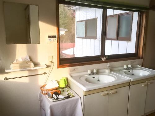 un baño con 2 lavabos y una ventana por encima en Wafu Guesthouse Kashiwaya, en Fujikawaguchiko
