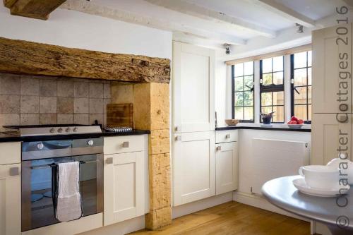 a kitchen with white cabinets and a stove top oven at The Brew House in Chipping Campden