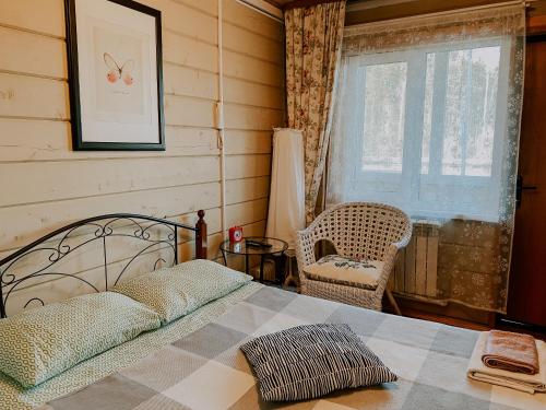 a bedroom with a bed and a chair and a window at Uralsky Teremok Hotel in Yekaterinburg