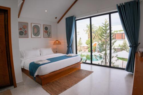 a bedroom with a bed and a large window at Montagne Residence in Kampot