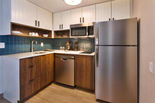 a kitchen with a stainless steel refrigerator and wooden cabinets at Staybridge Suites Pittsburgh Airport by IHG in Pittsburgh