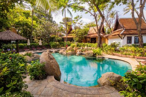 a swimming pool in a garden with rocks and a house at Anavana Beach Resort in Chaweng