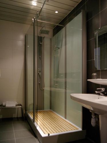 a shower with a glass door next to a sink at Hôtel Jeanne d'Arc in Lourdes