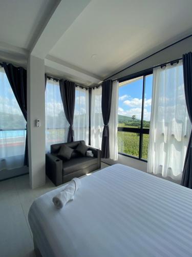 a bedroom with a bed and a couch and windows at 88 ลิฟวิ่ง โฮเทล ปากช่อง in Ban Sathani Bandai Ma