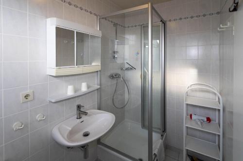 baño blanco con ducha y lavamanos en An der Düne 2, Whg 1, en Hörnum
