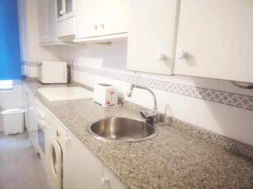 encimera de cocina con fregadero y armarios blancos en Apartamento CONFORT BEACH, 300 mtr playa, en Gijón