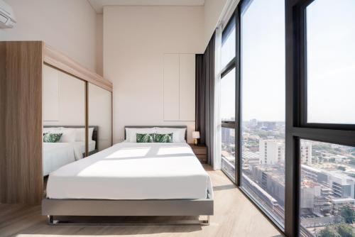 a bedroom with a white bed and large windows at Ramada By Wyndham Bangkok Sukhumvit 87 in Bangkok