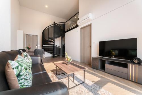 a living room with a couch and a tv at Ramada By Wyndham Bangkok Sukhumvit 87 in Bangkok