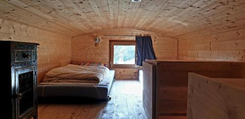 um pequeno quarto com uma cama num chalé de madeira em Le Petit Rias en Roulotte, 4 personnes, coin cuisine et cabinet de toilette em Saint Maurice en Chalencon
