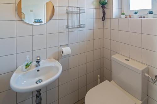Baño blanco con aseo y lavamanos en Ferienhaus Strandläufer, en Nessmersiel