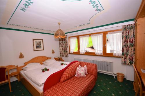 レッヒにあるPension Schafbergのベッドと赤いソファが備わるホテルルームです。