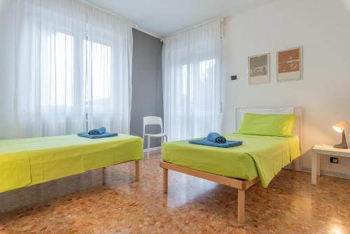 two beds in a room with yellow sheets at Appartamenti Matteotti 54 in Biandrate