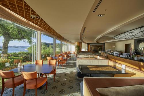 a restaurant with tables and chairs and a view of the ocean at Hotel Harvest Nankitanabe in Tanabe