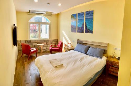 1 dormitorio con 1 cama y 2 sillas rojas en Matsu Island View Restaurant Bed and Breakfast en Nangan