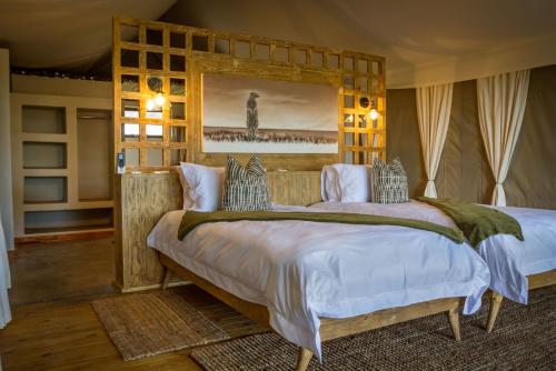 a bedroom with a large bed with a wooden headboard at Imagine Africa Luxury Tented Camp in Balule Game Reserve