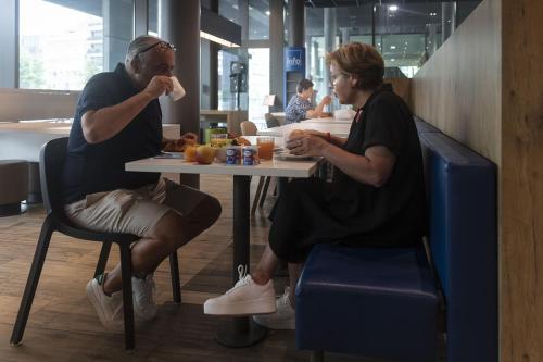 
two women sitting at a table in a restaurant at ibis budget Blankenberge in Blankenberge
