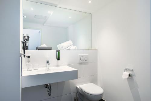 a white bathroom with a sink and a toilet at ACHAT Hotel Stuttgart Zuffenhausen in Stuttgart