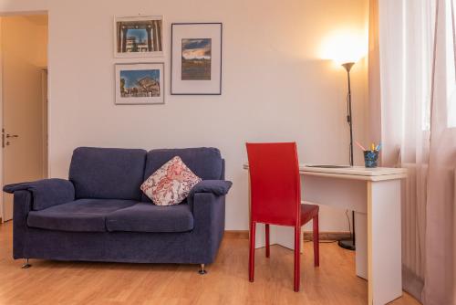 a living room with a blue chair and a desk at Appartamenti Matteotti 54 in Biandrate