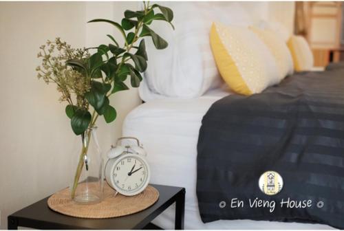 a alarm clock sitting on a table next to a bed at EnVieng House(อองเวียงเฮ้าส์): CM old city, Wat Phrasing in Chiang Mai