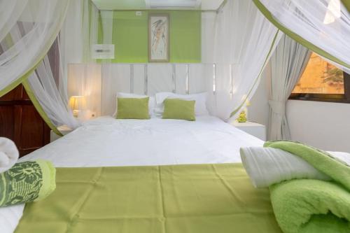 um quarto com uma grande cama branca com almofadas verdes em Casa Quimera em Maputo