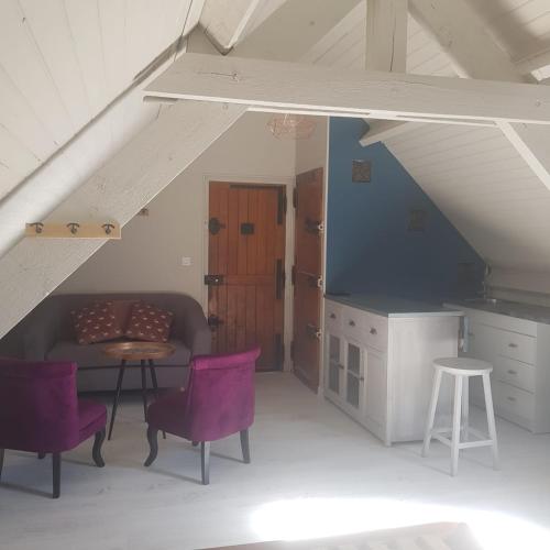 a kitchen with purple chairs and a table in a attic at Les gîtes équestre de ninon in Moult