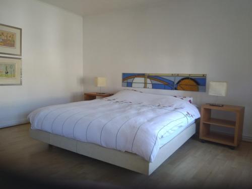 a bedroom with a white bed and a night stand at gezellig vakantiehuis te Maissin in Maissin