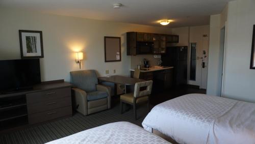 a hotel room with a bedroom with two beds and a kitchen at Candlewood Suites-West Springfield by IHG in West Springfield