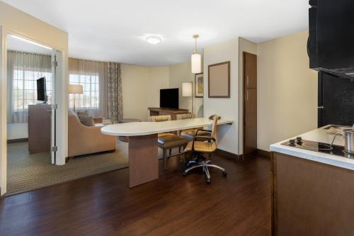 a room with a desk and a kitchen with a table at Candlewood Suites-West Springfield by IHG in West Springfield