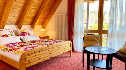 a bedroom with a bed and a table and a window at 4-Sterne Ferienhaus Rösslewiese Hinterzarten in Hinterzarten