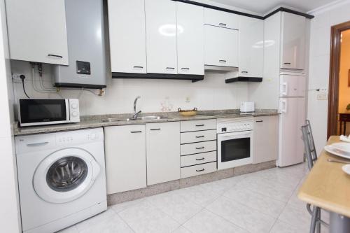 a kitchen with white cabinets and a washing machine at Casa Goros I in Melide