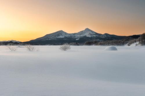 a snow covered field with mountains in the background at Lakeside Hotels Kuore in Kitashiobara