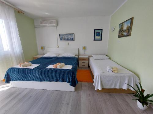a bedroom with two beds with blue and white sheets at Apartment KRUNO in Selce