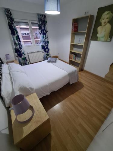 a bedroom with a white bed and a wooden floor at Dos Torres Miraflores - Parking privado gratis in Zaragoza