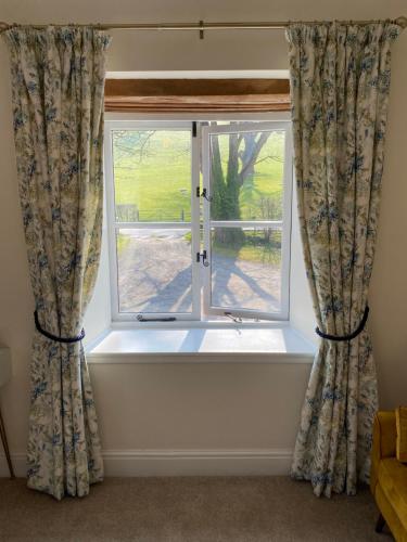 a window with curtains with a view of a yard at Black Mountain Lodge in Glasbury