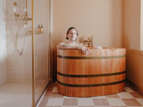 a man sitting in a wooden tub in a bathroom at BEAUSiTE Zermatt in Zermatt