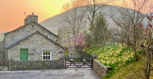 a stone house with a green door and a fence at Cross Haw Cottage in Sedbergh