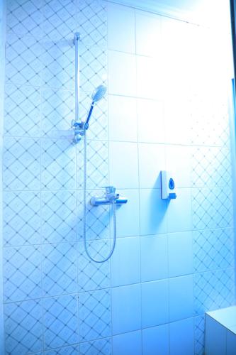 a shower in a bathroom with blue tiles at Victoria Hotel Apartment in Addis Ababa