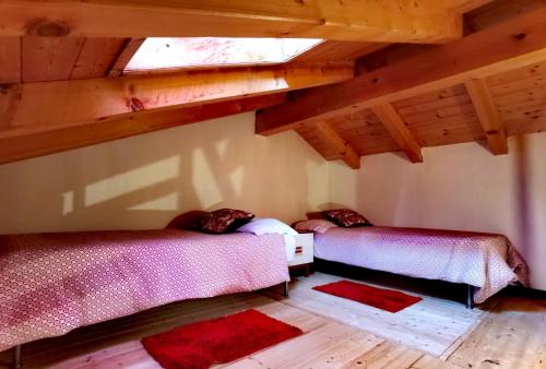 two beds in a room with wooden ceilings at APARTHOTEL STREMBO in Strembo